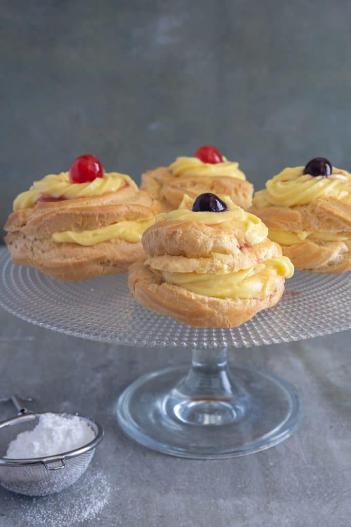 Four pastries on a a glass cake stand.