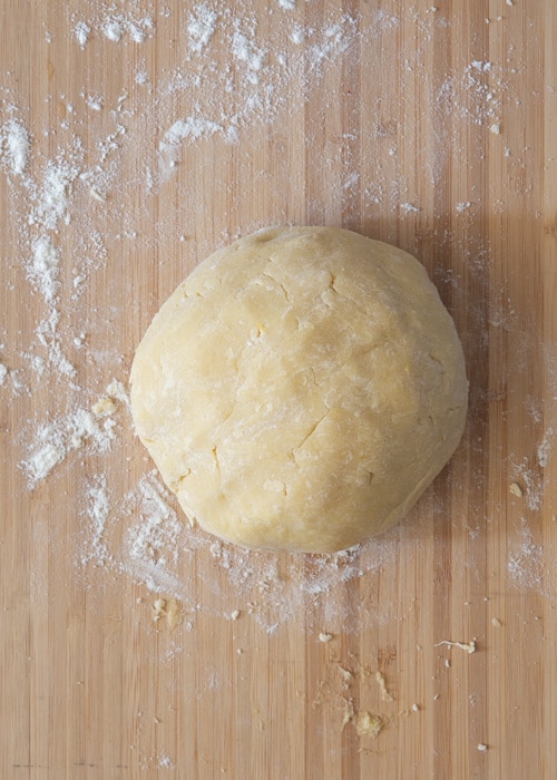 Dough formed into a ball on a wooden board.