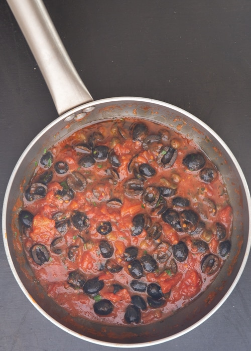 The sauce cooked with olives in the pan.