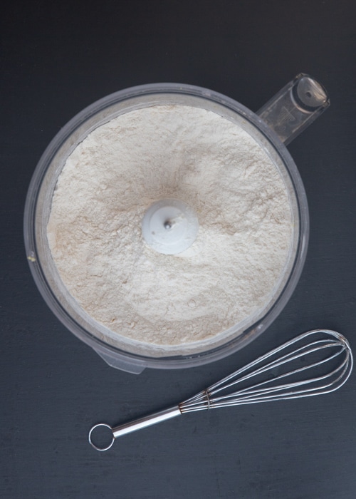 Dry ingredients whisked in the bowl of a food processor.