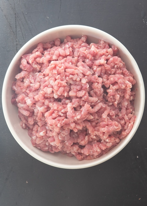 The pork pieces ground in a white bowl.