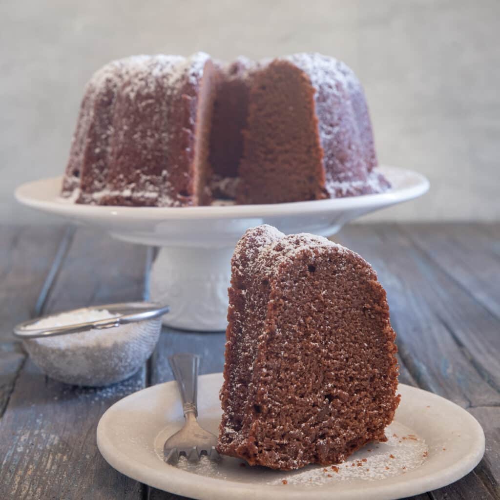 Chocolate cake with a slice on a white plate.