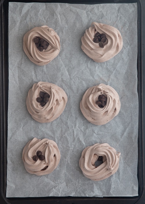 The meringue clouds baked and filled with chocolate chips on the baking sheet.