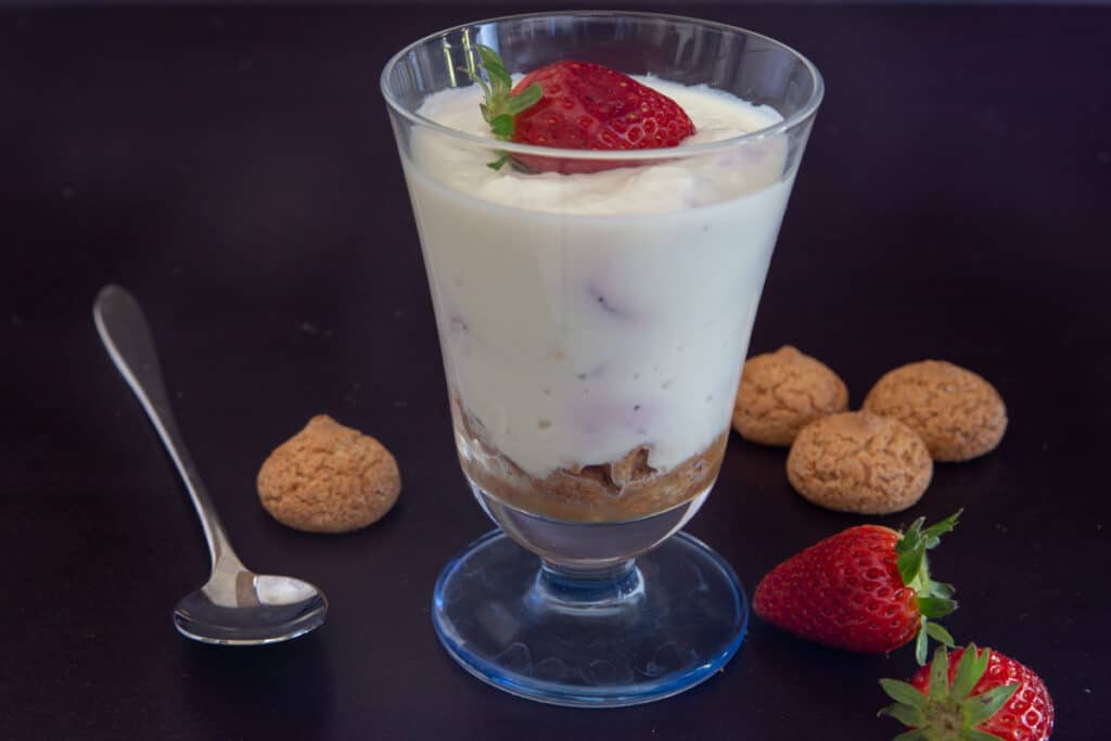 A glass of ricotta cream with cookies and strawberries.