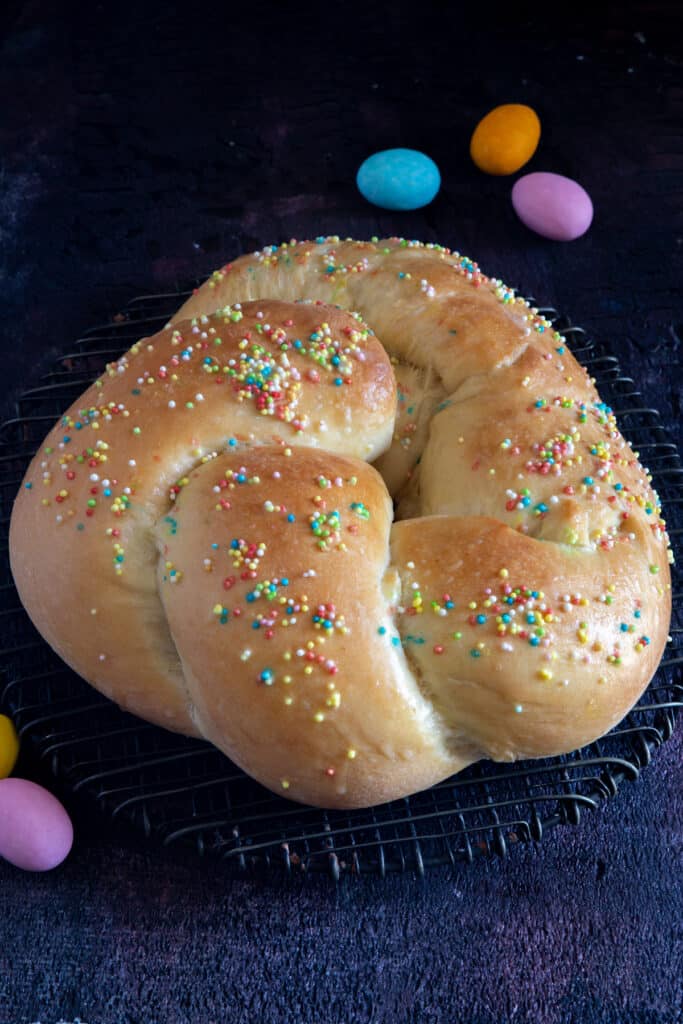 Sourdough Easter bread on a black board with 4 colored chocolate eggs.