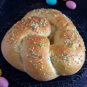 Sourdough Easter bread on a black board with 4 colored chocolate eggs.