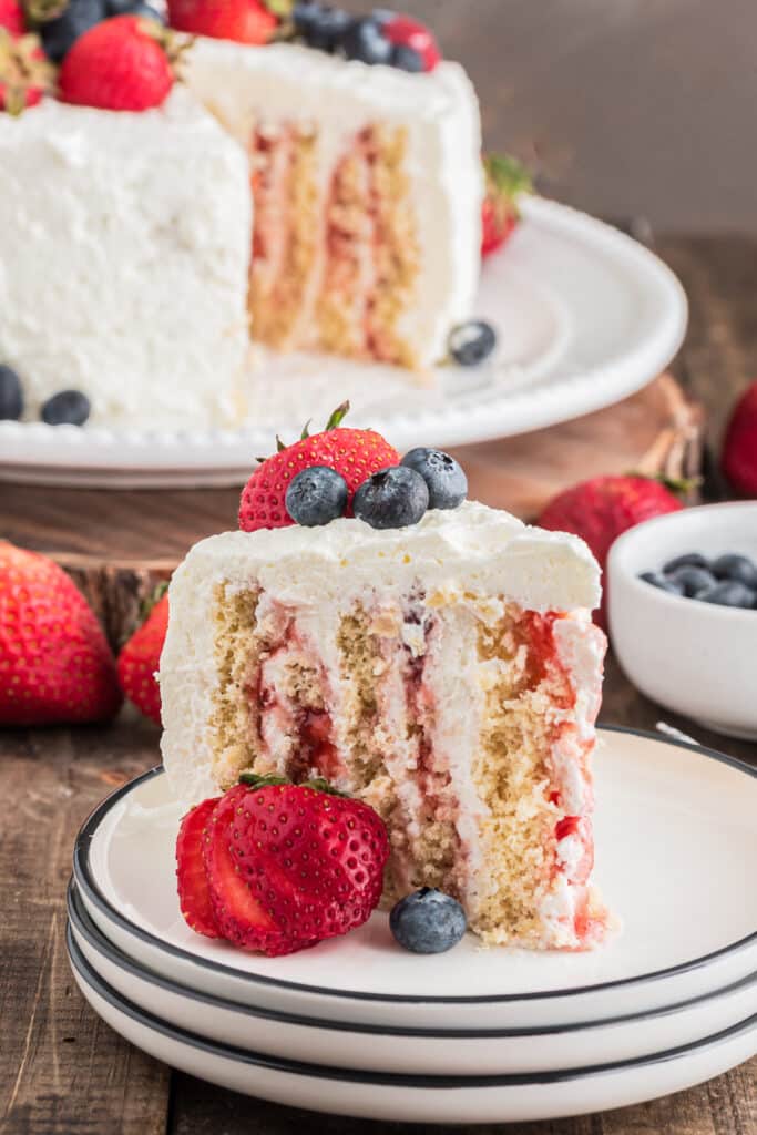 Cake on a cake plate and a slice on a white plate.