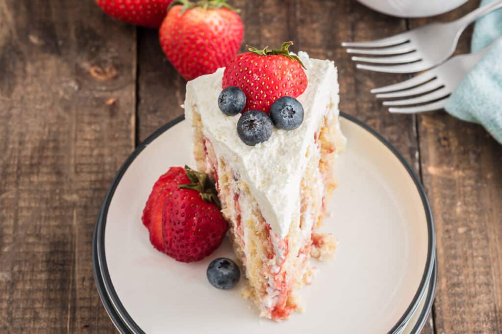 A slice of strawberry cake on a white plate.