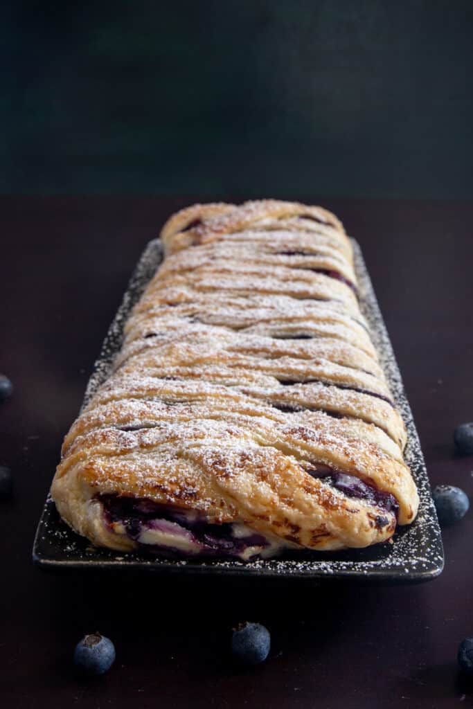 Blueberry strudel on a black plate.