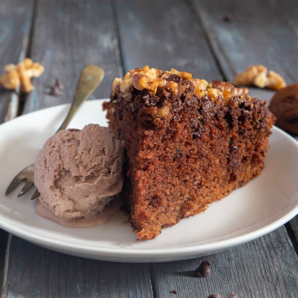 A slice of cake with a scoop of chocolate ice cream on a white plate.