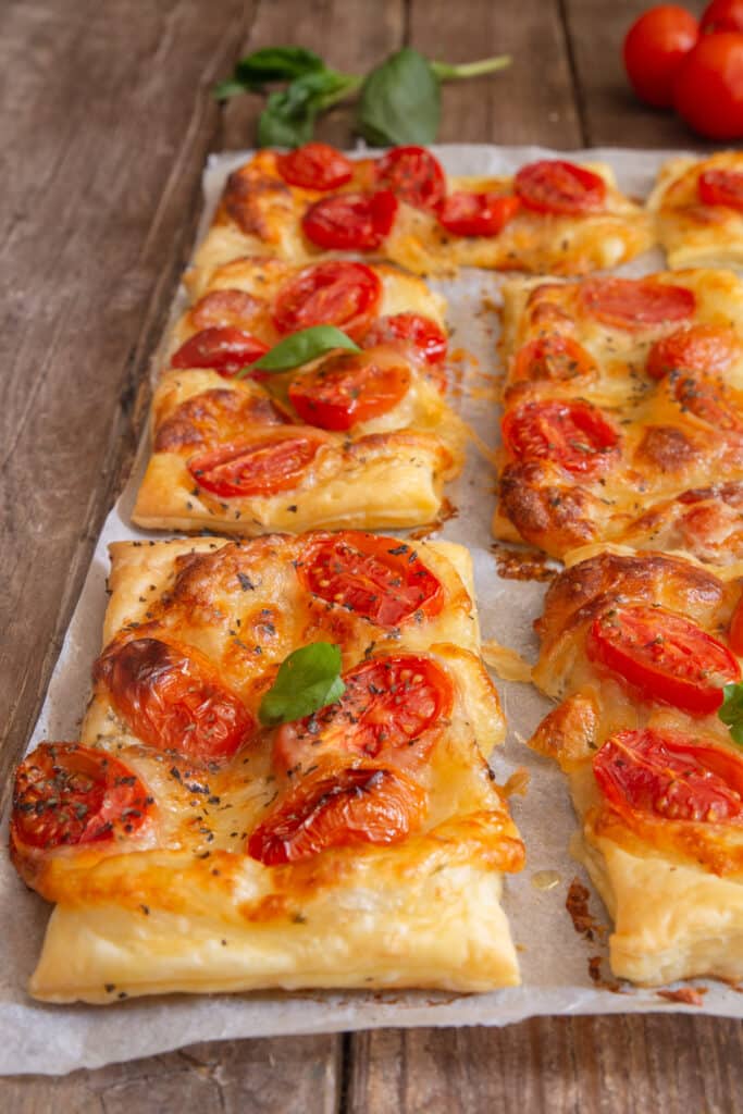Puff pastry tomato appetizers on parchment paper.