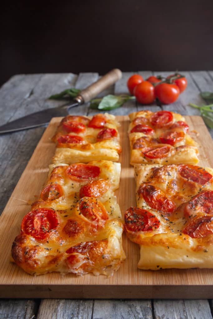 Puff pastry tomato appetizers on a wooden board.