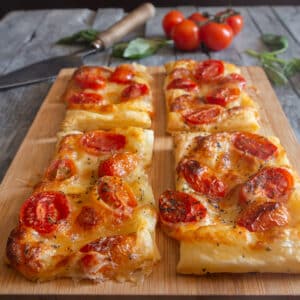 Puff pastry tomato appetizers on a wooden board.