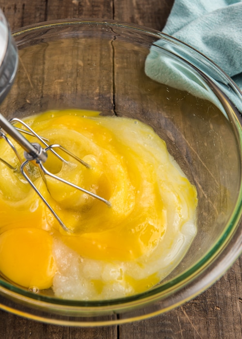 Mixing the eggs and sugar in a glass bowl.