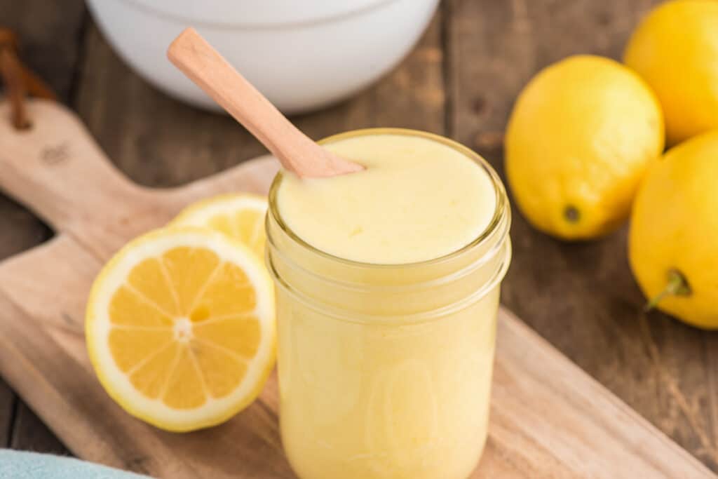 Lemon curd with a spoon in a jar.