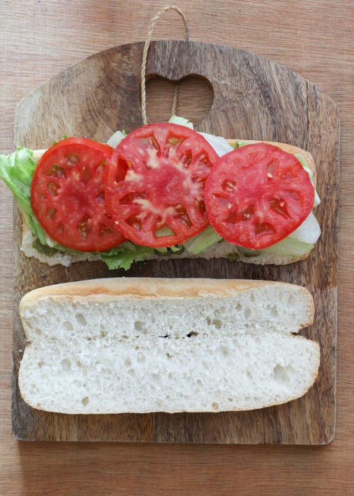 Adding the lettuce and tomatoes to the sandwich.
