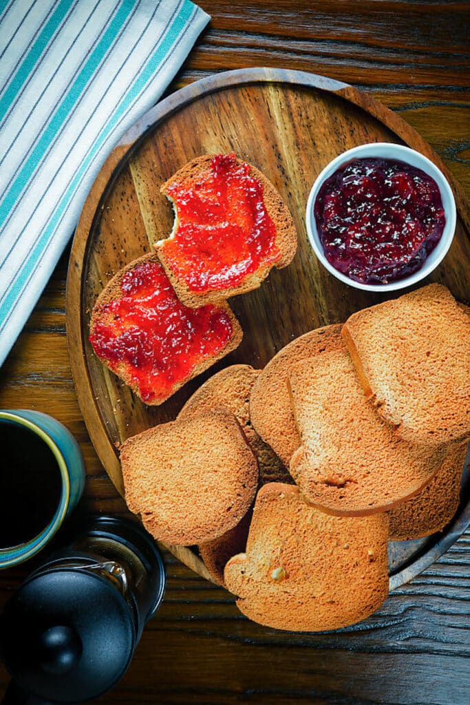 Breakfast biscotti on a wooden board with some jam.