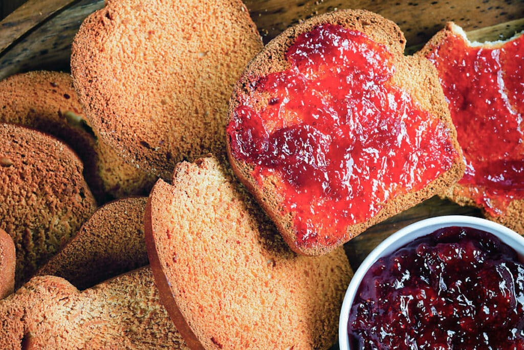 Breakfast biscotti on a wooden board with some jam.