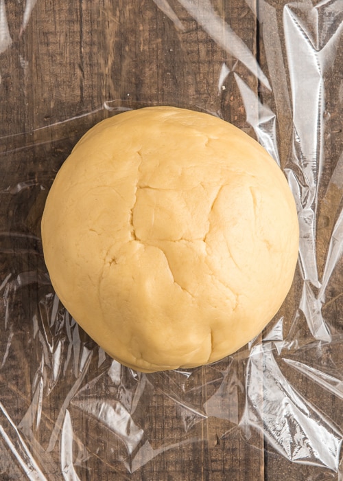 The dough formed into a ball on plastic wrap.