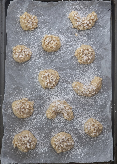 The cookies on the baking pan sprinkled with powdered sugar before baking.