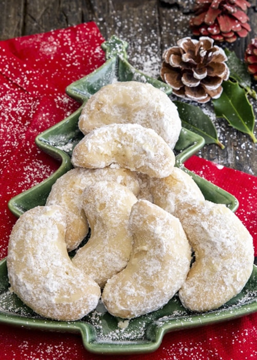 Almond crescent cookies on a green Christmas tree plate.