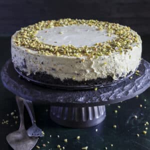 Pistachio cheesecake on a black cake stand.