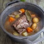 Pot roast with vegetables in a black pot.