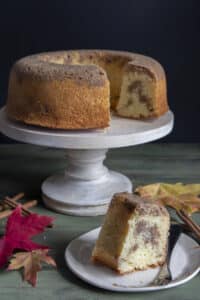 Cinnamon upside down cake on a cake stand with a slice on a white plate.