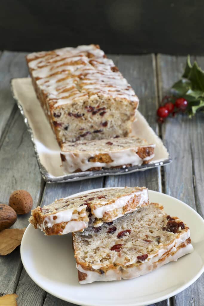 Cranberry banana loaf with two slices cut on a white plate.