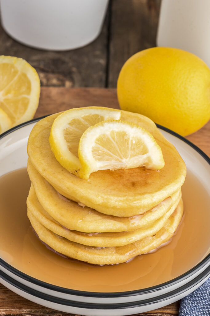 Lemon pancakes with syrup and lemon slices.