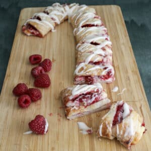 Candy cane puff pastry on a wooden board with two slices cut.