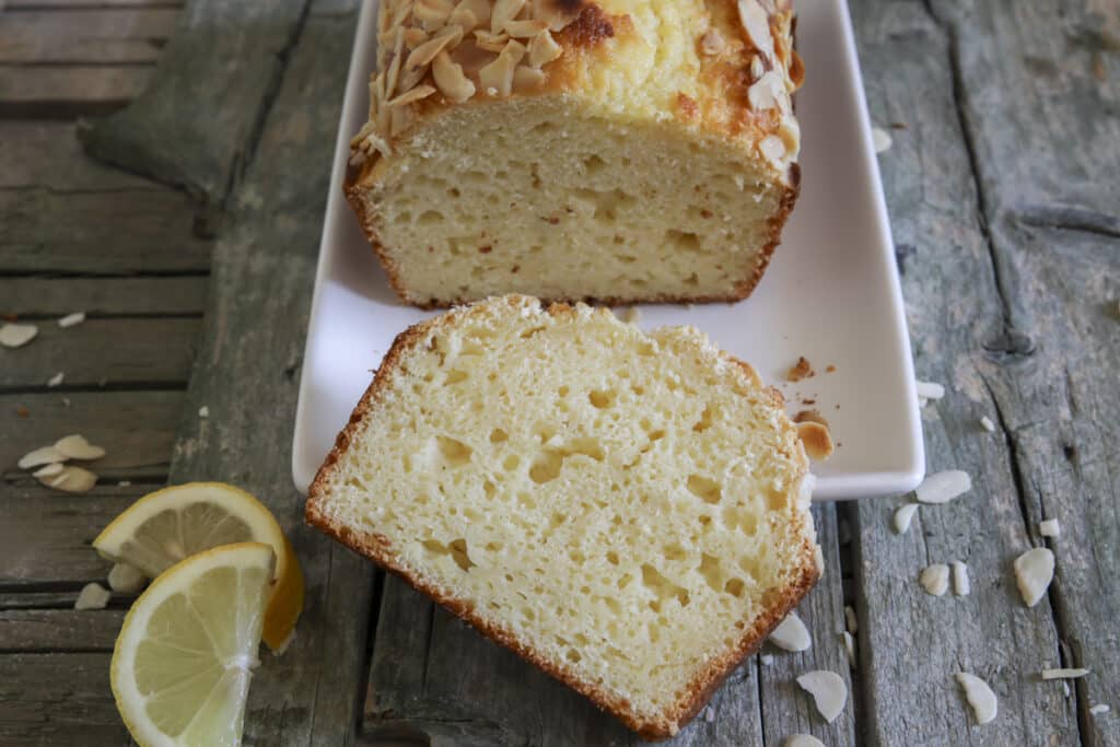 Lemon bread with a slice cut on a white plate.
