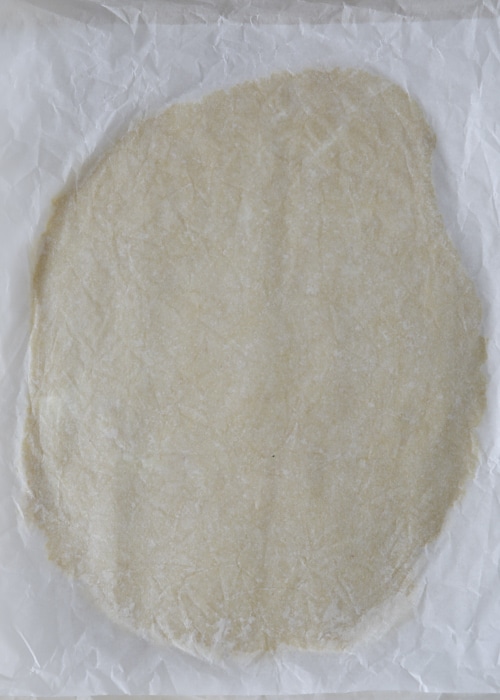 Dough rolled between parchment paper.