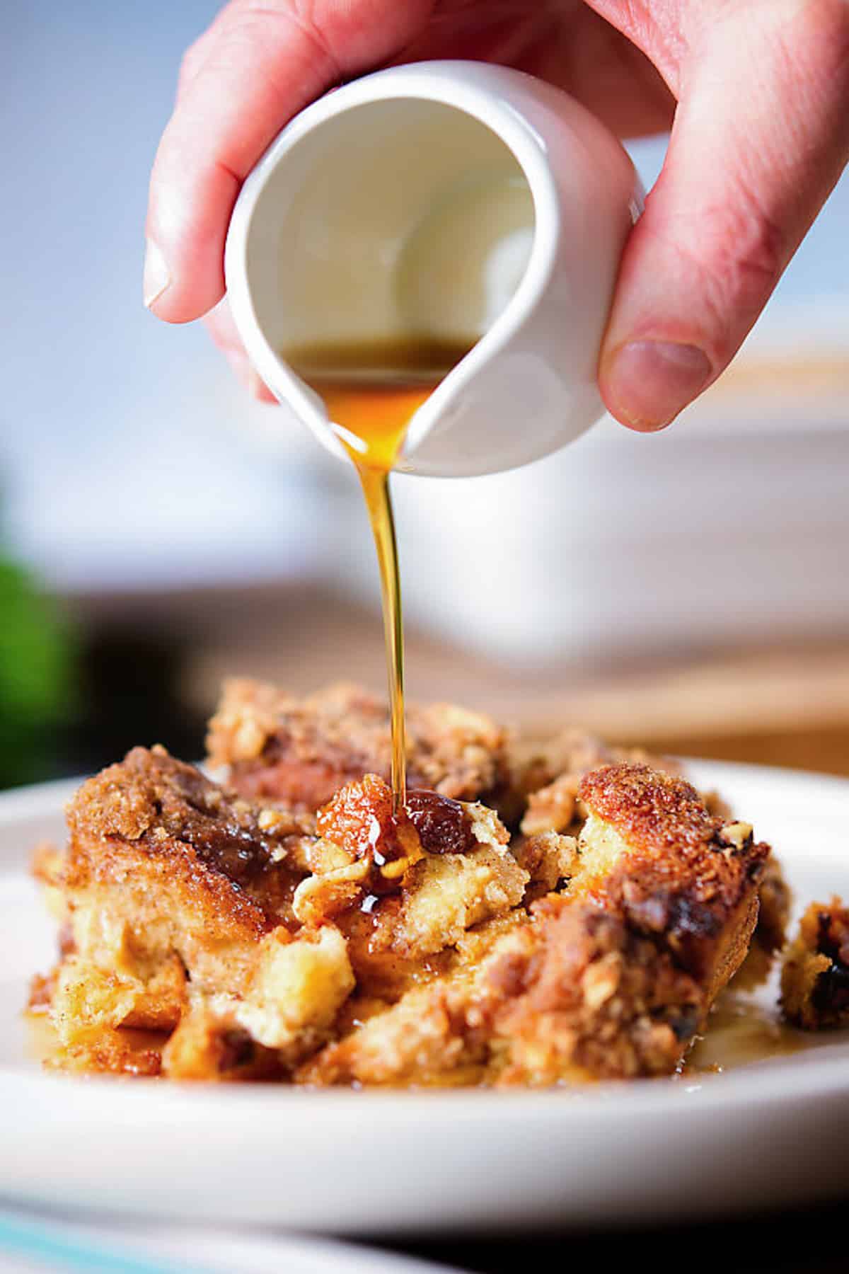 Pouring syrup on a slice of casserole.