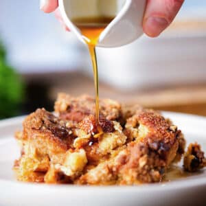 Pouring syrup on a slice of casserole.