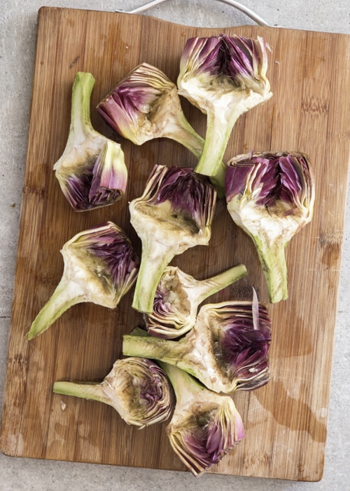 The cleaned artichokes on a wooden board.