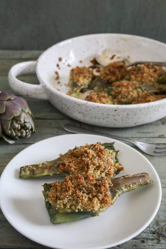 Artichokes in the pan and two on a plate.