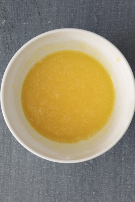 Egg yolks, butter and juice in a small white bowl.