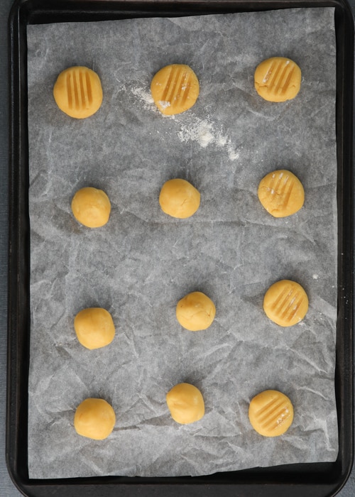 The dough balls on a parchment paper lined baking sheet before baking.