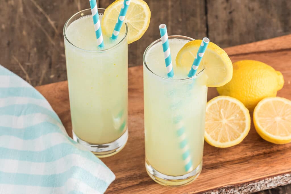 Two glasses of frozen lemonade with blue and white straws.