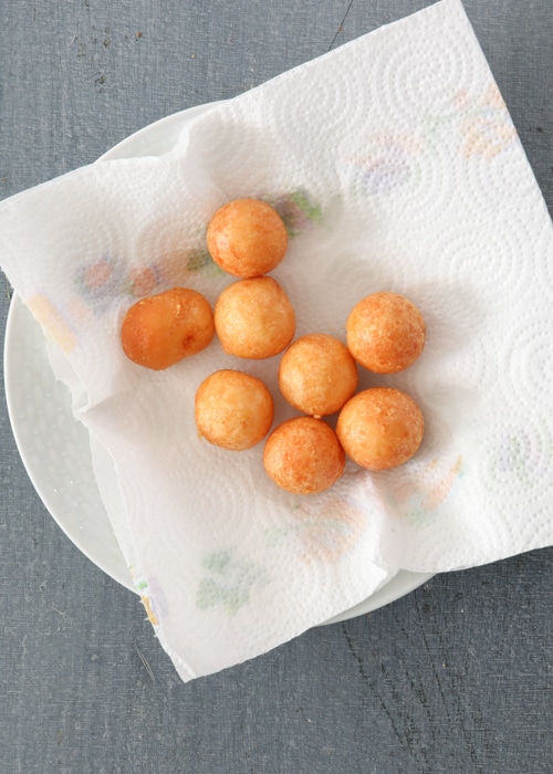 The fried cheese balls on a paper towel lined dish.
