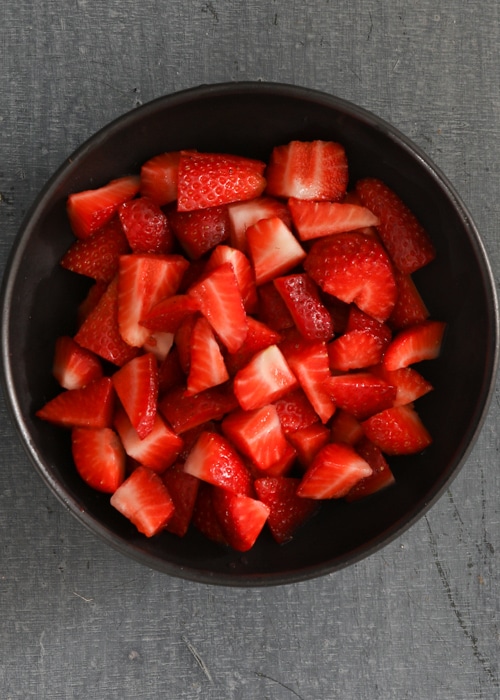 The chopped strawberries in a black bowl.