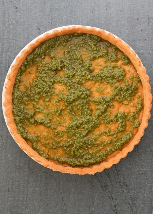 The bottom of the crust spread with pesto.