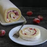 Cake roll on a white plate with a slice on a small white plate.