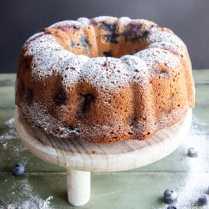 Blueberry pound cake on a white cake stand.