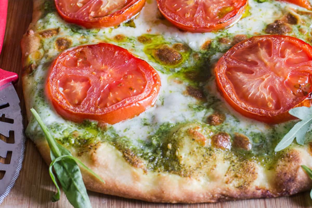 Pesto pizza on a wooden board.