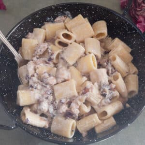 Radicchio pasta in a black skillet with a silver spoon.