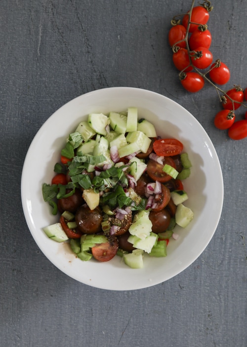 Vegetables for the salad in a white bowl.