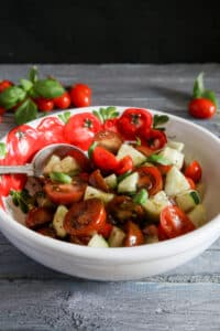 Tomato salad in a white bowl with tomatoes on it.