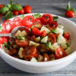 Tomato salad in a white bowl with tomatoes on it.